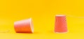 Two paper red cups with strings lying apart. Children`s homemade toy walkie-talkie. Yellow background. Copy space. Banner. The