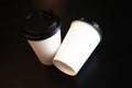 two paper white cups with a plastic black lid for takeaway coffee on a black background Royalty Free Stock Photo