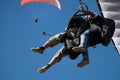 Two paraglider tandem fly against the blue sky