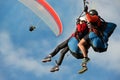 Two paraglider tandem fly against the blue sky