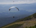 Two paragliders fly over a mountain valley on a sunny summer day. Kiting in blue and orange kite in tatra mountains Royalty Free Stock Photo