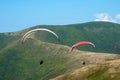 Two paragliders fly over a mountain valley on a sunny summer day. Royalty Free Stock Photo