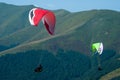 Two paragliders fly over a mountain valley on a sunny summer day. Royalty Free Stock Photo