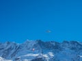 Two paragliders in front of a snow covered mountain ridge in Switzerland