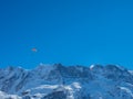 Two paragliders in front of a snow covered mountain ridge in Switzerland