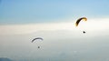 Two paragliders paragliding above misty valley