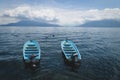 Two parallel swimming blue boats on lake Atitlan with view on volcanoes in Santa Cruz la Laguna, Guatemala