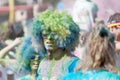 Two partpicients wearing large wigs and covered with blue and gr