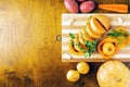 Two parts of an oblong pumpkin decorated with parsley and dill, garlic and turnips on a bamboo cutting Board, and a round pumpkin