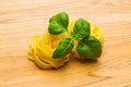 Two pasta noodle nests with basil