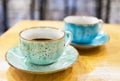 Two pastel green and blue colour cups of coffee on a shabby wooden table