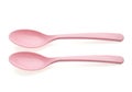 Two pastel pink plastic spoons resting on a white background Royalty Free Stock Photo