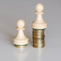 Two pawns chess pieces on columns of coins, symbolizing a sharp income inequality