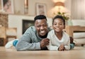 Two peas in a pod. Full length portrait of a handsome young man and his son lying on the living room floor at home. Royalty Free Stock Photo