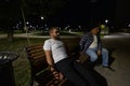 Two pensive men sit on a bench in the park at night in the summer. Two friends are resting thoughtfully on a summer Royalty Free Stock Photo