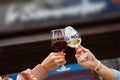 Two people clinking glasses with red and white wine