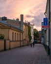 Two people cycling through a cobblestoned street during sunset in the historic old town of Lund, Sweden