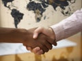 Two people of different ethnicities shaking hands over a world map.. AI generation