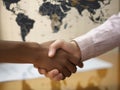 Two people of different ethnicities shaking hands over a world map.. AI generation Royalty Free Stock Photo