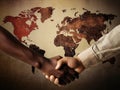 Two people of different ethnicities shaking hands over a world map.. AI generation Royalty Free Stock Photo