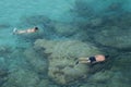 Two people do snorkeling near the rocks