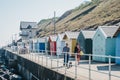 Two people with a dog  walking by colourful beach huts by the sea in Sheringham, Norfolk, UK Royalty Free Stock Photo