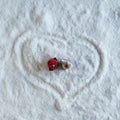 Two people dolls in winter clothes in the shape of heart on the snow. Aerial, top view. Concept of date valentine`s day