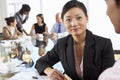 Two People Having Meeting Around Glass Table In Boardroom With Colleagues In Background Royalty Free Stock Photo