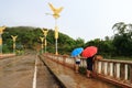 Two people hold umbrellas on the bridge