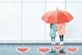 Two people holding umbrella in rain, surrounded by heart shapes on ground, conveying love and connection
