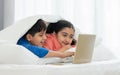 Two people, Indian teenage brother, sister smiling, using laptop to online learning, do homework, watching movie together with fun