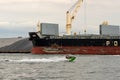Two people on jet ski in front of shipping freighter boat