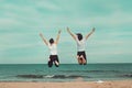 Two people jumping by the sea. Concept of fun on the beach. Royalty Free Stock Photo