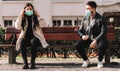 Two people keep their distance - covid-19 social distancing concept picture with three people wearing face masks - stay away