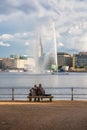 Two people look at the fountain in the center of Hamburg.