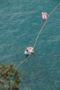 Two people lying on a rubber boat take the sun in the middle of the sea. A rope ties them to the ground. View from the air