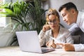 Two people male female working together in home office workplace with laptop and documents. Young man and adult woman team using Royalty Free Stock Photo