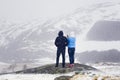 Two people, a man and a woman admire the winter landscape of the Norwegian mountains and make a photo on the phone.