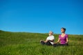 Two people meditating sitting in the field.