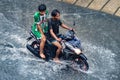 two people on a motorbike who drove through flood waters during heavy rain in a residential area