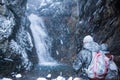 Two people near a waterfall in snow storm in Iceland