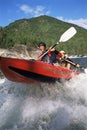 Two people paddling inflatable boat down rapids