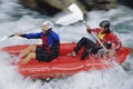 Two people paddling inflatable boat down rapids