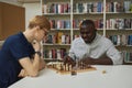 Two people playing chess in library with black man thinking of win strategy Royalty Free Stock Photo