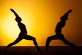 Two people practicing yoga in the sunset light Royalty Free Stock Photo