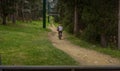 two people riding bicycles on a path through the forest and under the ski lifts of a ski resort Royalty Free Stock Photo