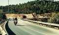 People riding motorcycles on the road surrounded by trees under the sunlight in Spain Royalty Free Stock Photo