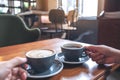 Two people`s hands holding coffee and hot chocolate cups on wooden table in cafe Royalty Free Stock Photo