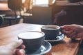 Two people`s hands holding coffee and hot chocolate cups on wooden table in cafe Royalty Free Stock Photo