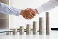 Two people shake hand with stacked of coin on wood table concept Royalty Free Stock Photo